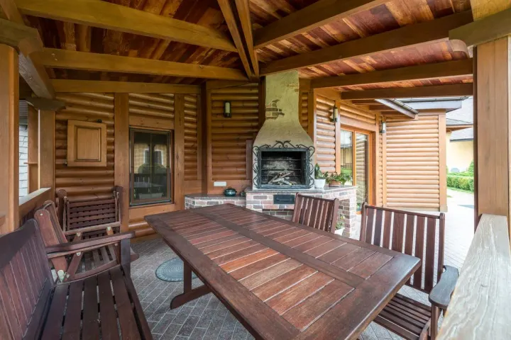 An outdoor fireplace with a brick base anchoring a covered timber patio