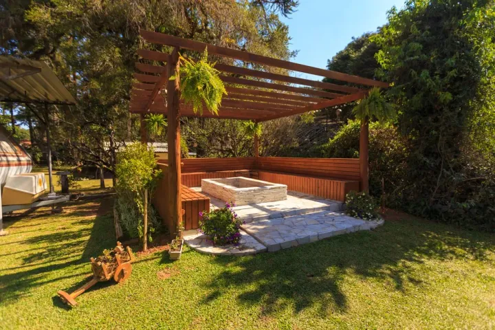 A corner pergola with built-in bench seating around a stone fire pit